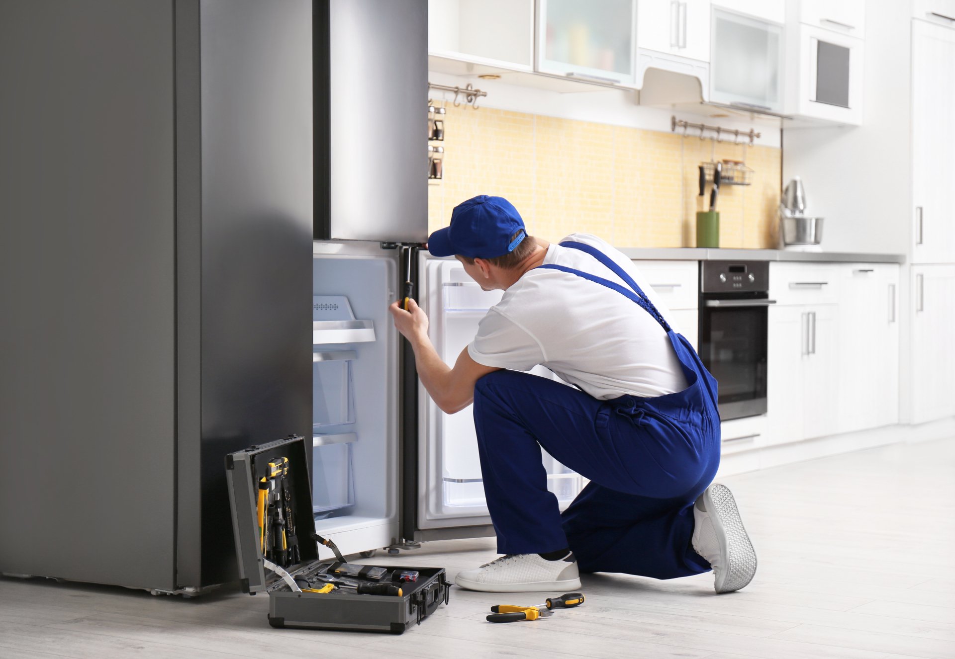 a technician repairing a refrigerator - Nextdoor Appliance Repair Charlotte