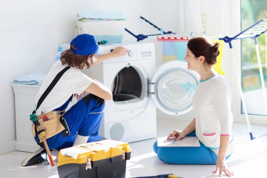 a technician repairing a washer while woman is watching - appliance repair service Charlotte